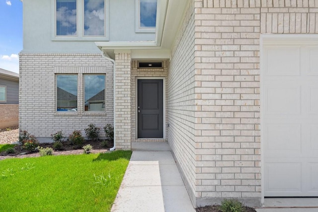 entrance to property featuring a garage and a lawn