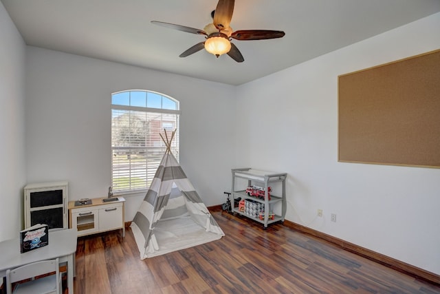 recreation room featuring a healthy amount of sunlight, baseboards, a ceiling fan, and wood finished floors