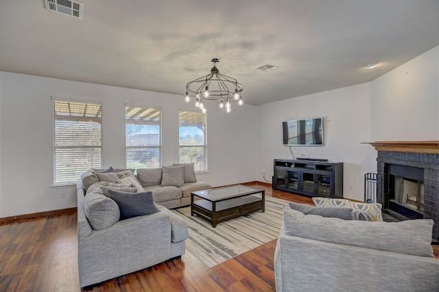 living area featuring a fireplace, wood finished floors, visible vents, and baseboards