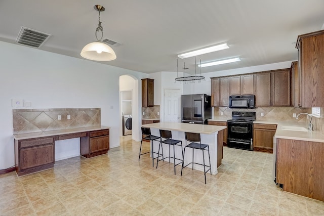 kitchen featuring a breakfast bar, arched walkways, visible vents, a sink, and black appliances