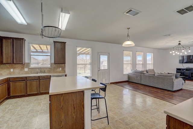 kitchen with light countertops, visible vents, backsplash, and a kitchen breakfast bar