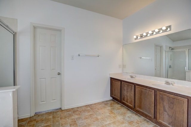 full bathroom featuring double vanity, a stall shower, baseboards, and a sink