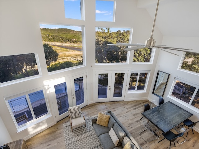 living room with light hardwood / wood-style flooring, a healthy amount of sunlight, ceiling fan, and a towering ceiling