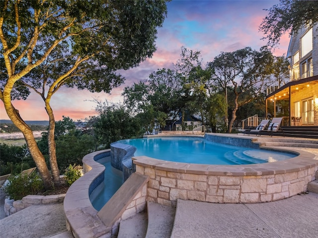 pool at dusk featuring a patio