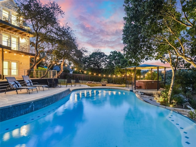 pool at dusk featuring a patio and a hot tub