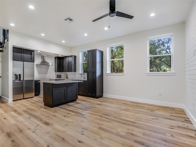 kitchen with light hardwood / wood-style floors, wall chimney exhaust hood, and ceiling fan