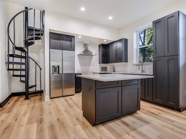 kitchen with a center island, wall chimney exhaust hood, backsplash, light wood-type flooring, and stainless steel refrigerator with ice dispenser