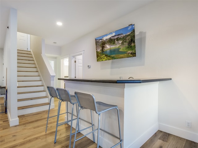 bar with white cabinetry and light wood-type flooring