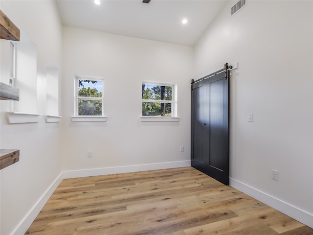 spare room featuring a barn door and light hardwood / wood-style flooring