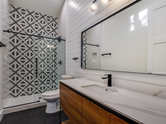 bathroom featuring tile flooring, tile walls, a shower with shower door, toilet, and vanity with extensive cabinet space