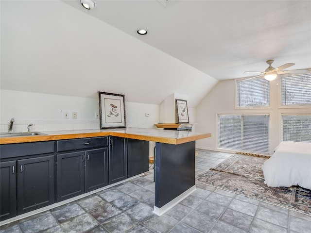 kitchen with butcher block counters, ceiling fan, sink, tile floors, and vaulted ceiling