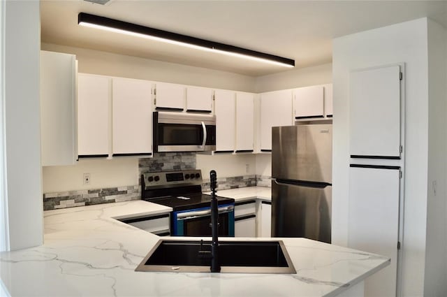 kitchen featuring light stone countertops, white cabinetry, tasteful backsplash, and stainless steel appliances