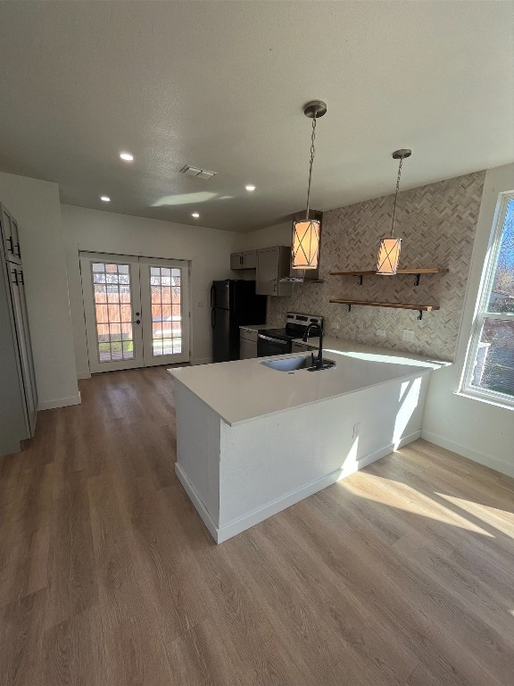 kitchen featuring black refrigerator, backsplash, dark hardwood / wood-style floors, stainless steel electric range, and pendant lighting