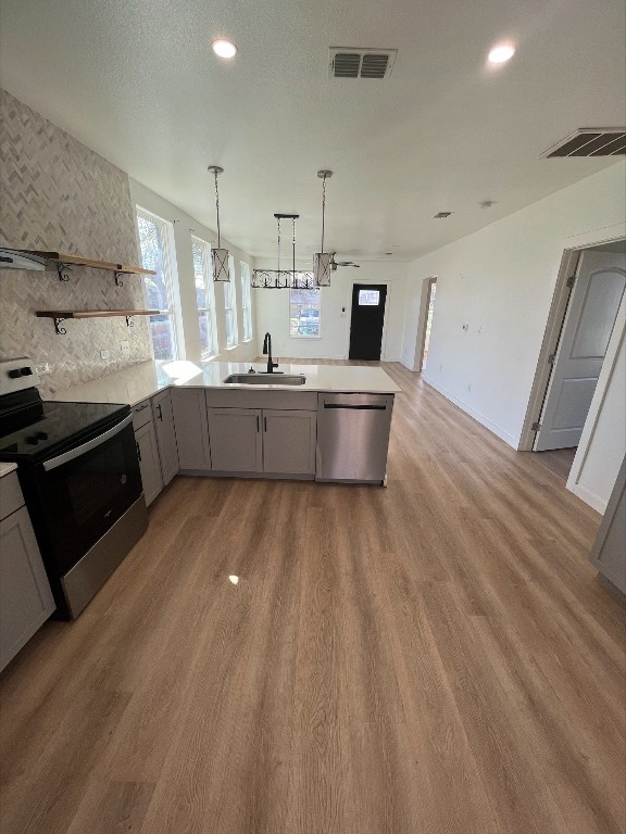 kitchen featuring appliances with stainless steel finishes, gray cabinetry, light hardwood / wood-style flooring, ceiling fan with notable chandelier, and sink