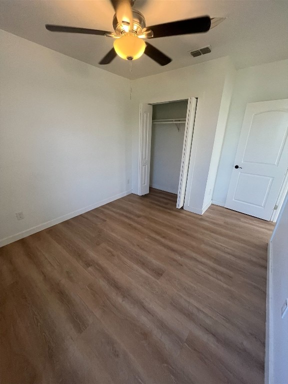 unfurnished bedroom featuring ceiling fan, a closet, and dark wood-type flooring