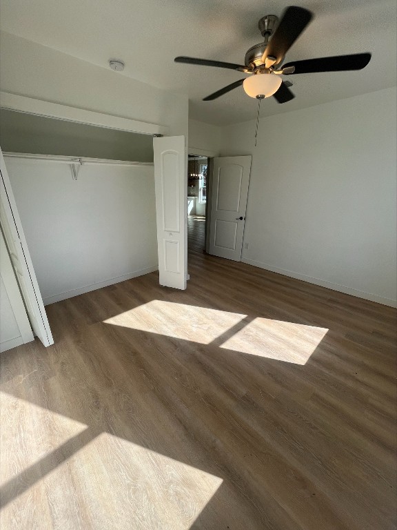 unfurnished bedroom featuring ceiling fan, dark wood-type flooring, and a closet