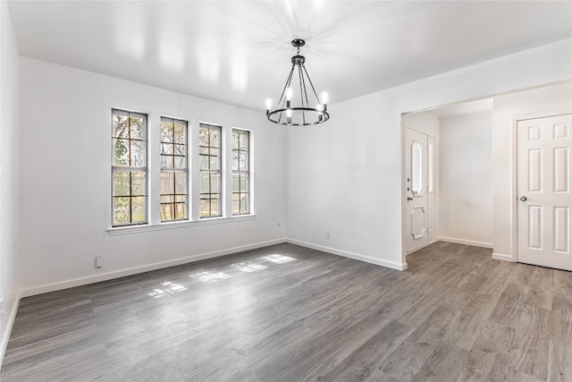 unfurnished room featuring a notable chandelier and dark hardwood / wood-style flooring