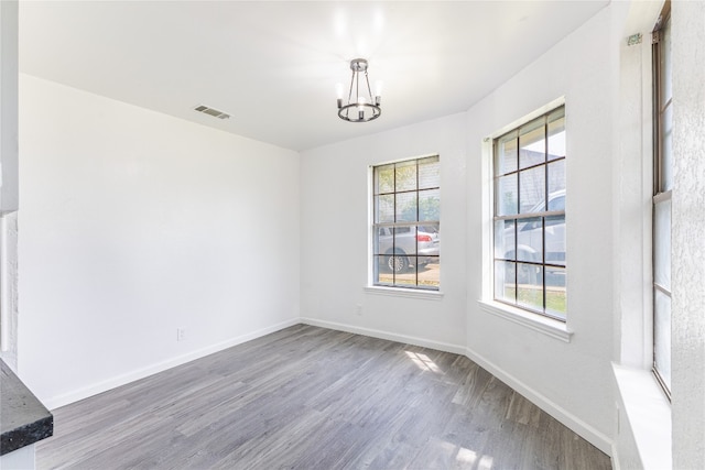 spare room with an inviting chandelier and hardwood / wood-style flooring