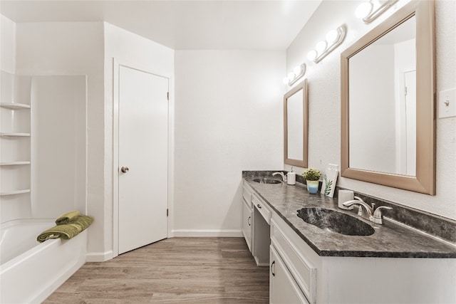 bathroom with large vanity, double sink, a bathtub, and hardwood / wood-style flooring