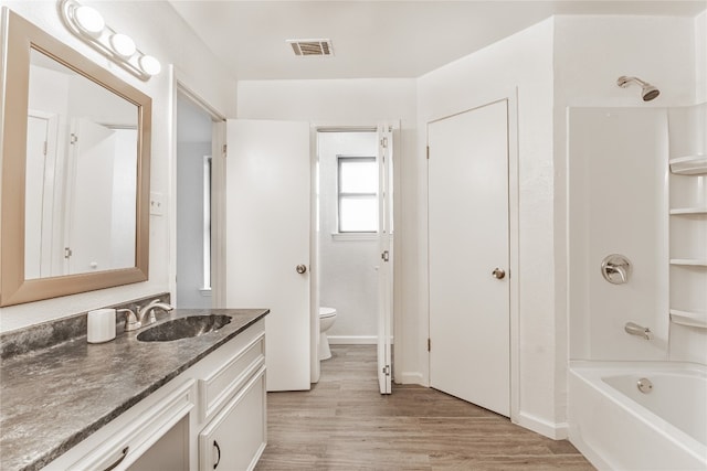 full bathroom with wood-type flooring, toilet, vanity, and shower / tub combination