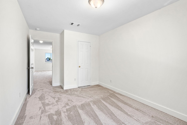 unfurnished bedroom with light colored carpet and a closet