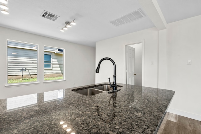 kitchen featuring dark stone countertops, sink, and wood-type flooring