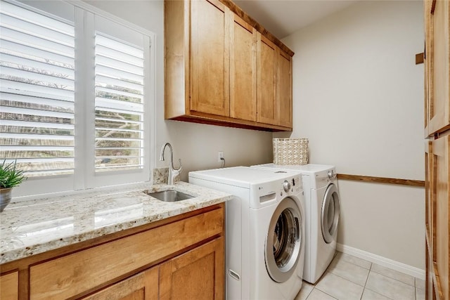 laundry room featuring cabinet space, light tile patterned flooring, a sink, independent washer and dryer, and baseboards