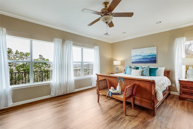 bedroom featuring ceiling fan, baseboards, crown molding, and wood finished floors