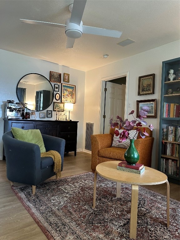 living room featuring ceiling fan, hardwood / wood-style floors, and a textured ceiling