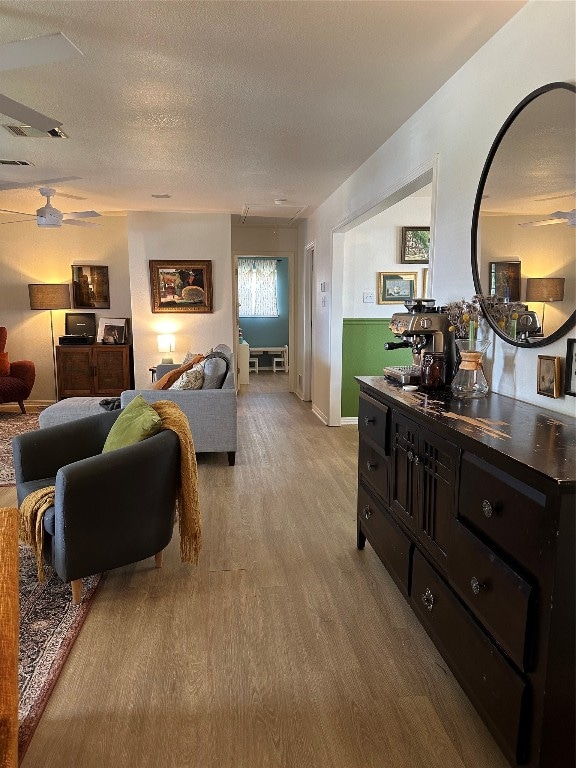 living room featuring ceiling fan, a textured ceiling, and hardwood / wood-style floors