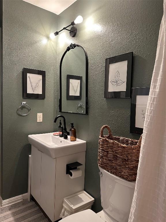 1301 NE 2nd St, Smithville, TX 78957 - bathroom with toilet, vanity, a textured wall, and baseboards