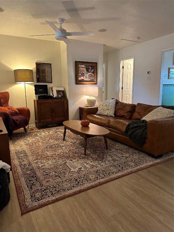 living room featuring ceiling fan, a textured ceiling, and hardwood / wood-style floors