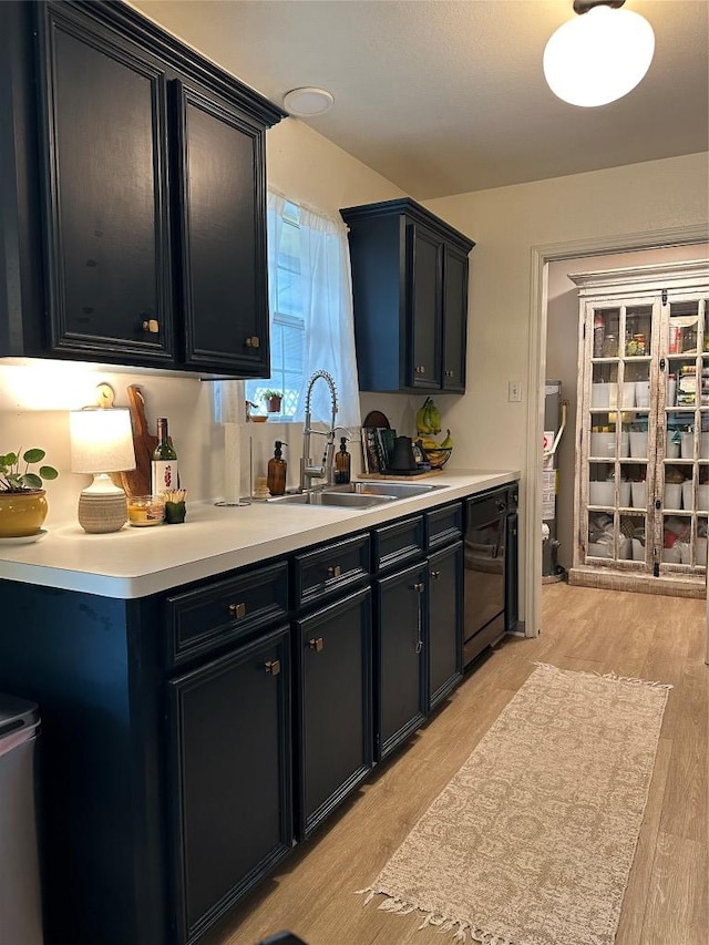 1301 NE 2nd St, Smithville, TX 78957 - kitchen featuring black dishwasher, a sink, dark cabinetry, and light wood-style flooring