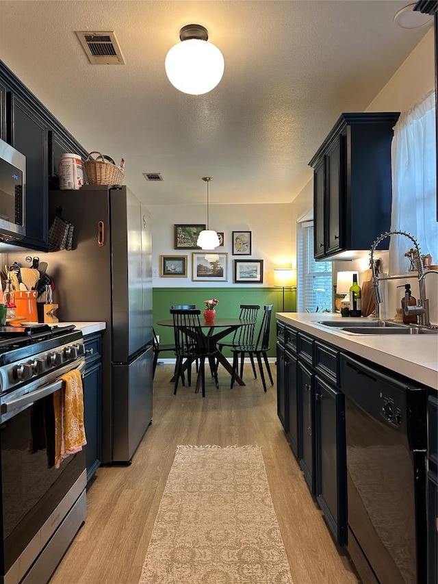 1301 NE 2nd St, Smithville, TX 78957 - kitchen with light countertops, visible vents, light wood-style flooring, stainless steel appliances, and a sink