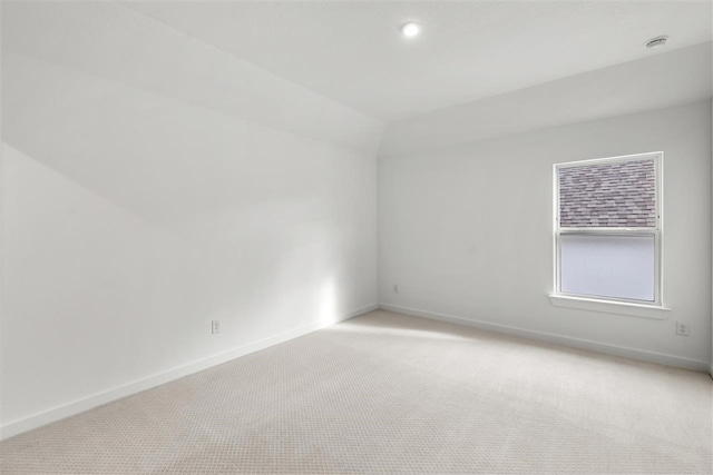 carpeted spare room featuring lofted ceiling