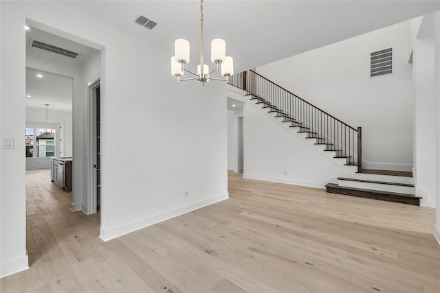 unfurnished dining area featuring light hardwood / wood-style flooring and a notable chandelier