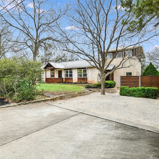 view of front of house featuring fence, a front lawn, and stucco siding