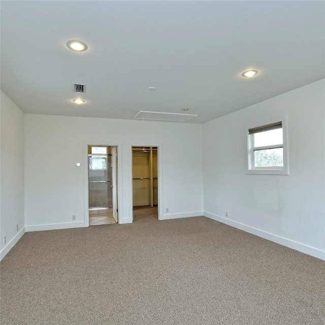 empty room featuring baseboards, attic access, visible vents, and carpet flooring