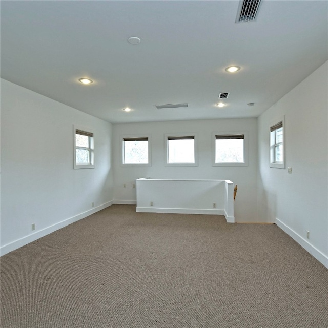 empty room with carpet, visible vents, baseboards, and recessed lighting