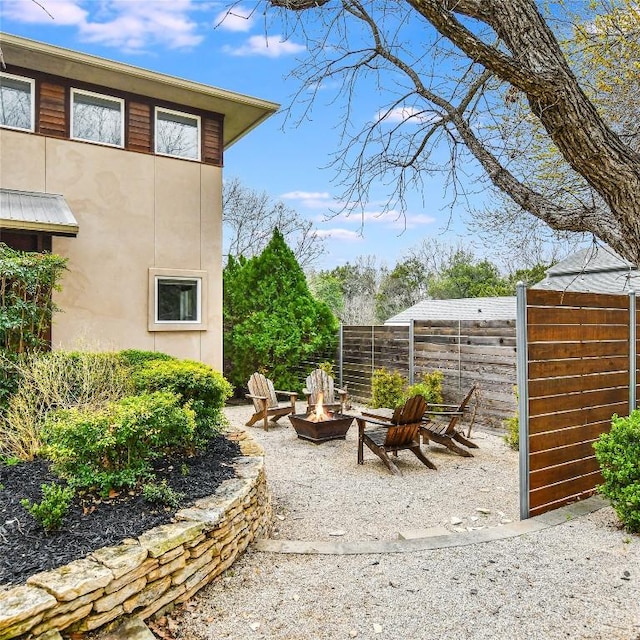 exterior space featuring an outdoor fire pit and fence