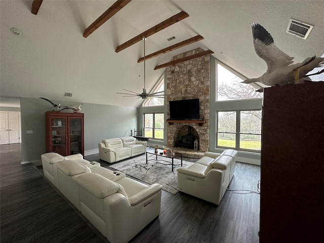 living room featuring a stone fireplace, dark hardwood / wood-style floors, and beamed ceiling