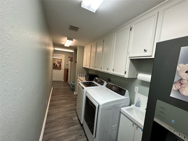 washroom featuring washing machine and dryer, dark wood-type flooring, and cabinets