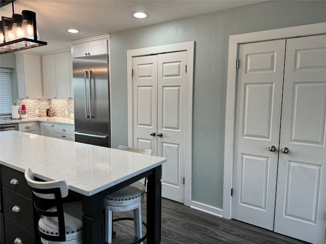 kitchen with built in fridge, dark hardwood / wood-style floors, pendant lighting, and white cabinetry