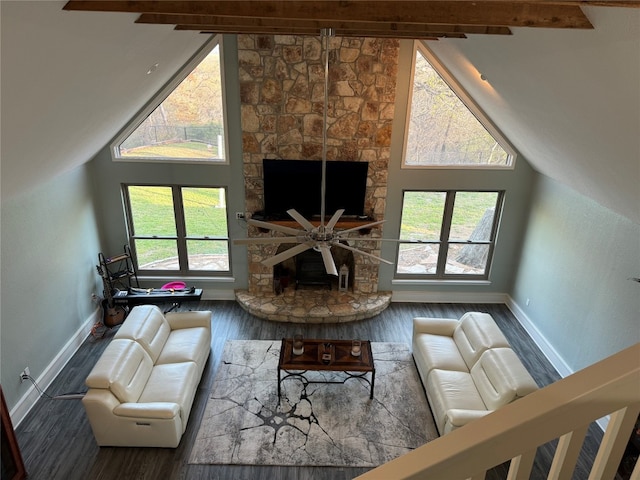 living room featuring dark hardwood / wood-style floors, ceiling fan, high vaulted ceiling, beam ceiling, and a stone fireplace