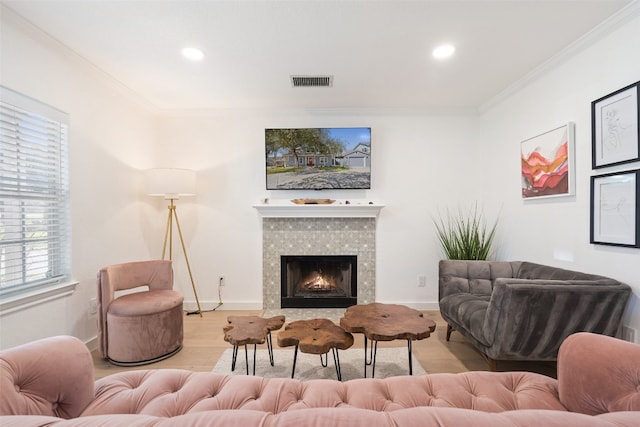 living room with a fireplace, light hardwood / wood-style flooring, and ornamental molding