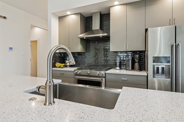 kitchen featuring backsplash, light stone counters, high end appliances, and wall chimney range hood