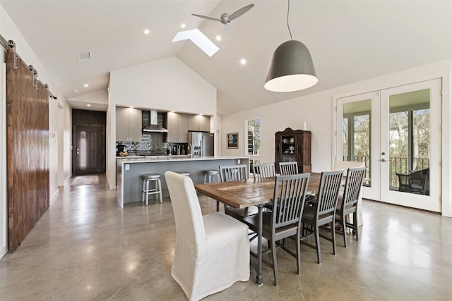 dining space with french doors, ceiling fan, a skylight, a barn door, and high vaulted ceiling