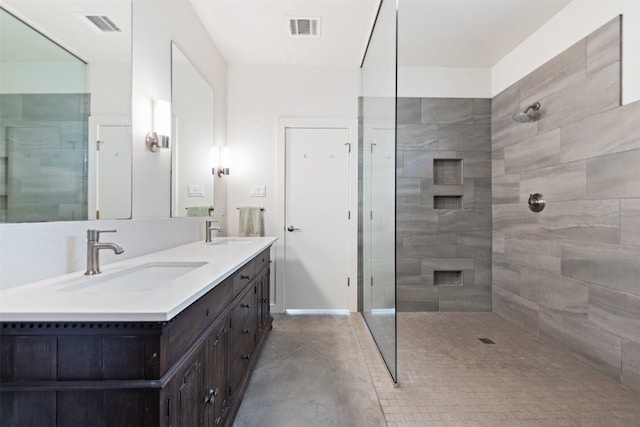 bathroom featuring double sink vanity, tile floors, and a tile shower