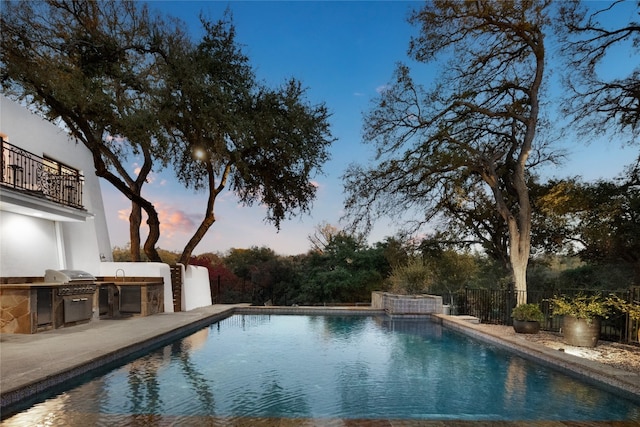 pool at dusk featuring area for grilling