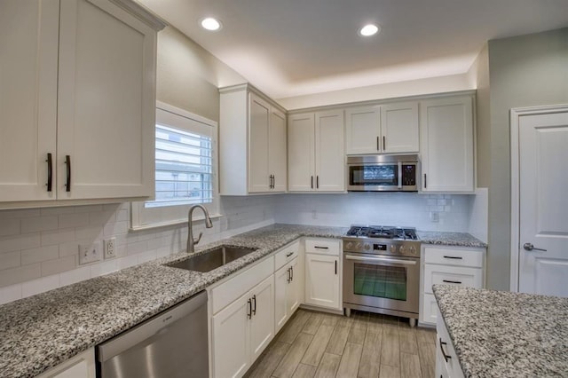 kitchen with backsplash, light stone counters, light wood-type flooring, and stainless steel appliances